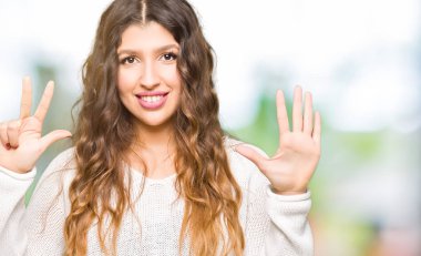 Genç güzel kadın giyiyor beyaz kazak gösterme ve parmakları ile işaret kendinden emin ve mutlu gülümseyerek süre sekiz numara.