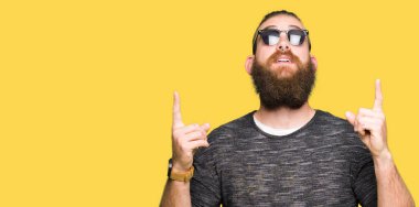 Genç hippi erkek güneş gözlüğü takıyor hayret ve yukarıya bakıp parmakları ile işaret şaşırttı ve silah kaldırdı.