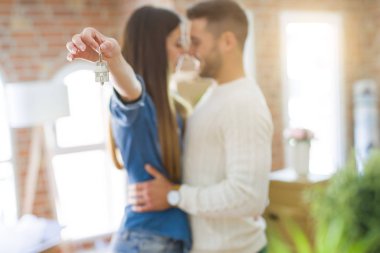 Genç çift yeni bir eve hareket, yeni dairenin anahtarlarını gösteren aşk sarılmak çok mutlu gülümseyen