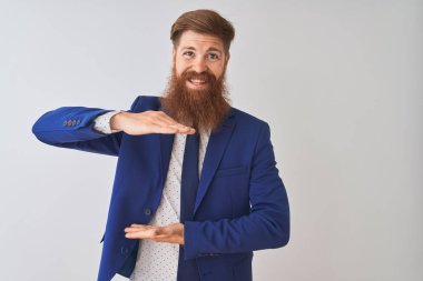 İzole edilmiş beyaz arka plan üzerinde duran takım elbiseli genç kızıl saçlı işadamı. Ellerinde büyük ve büyük bir işaret, ölçü sembolü var. Kameraya bakıp gülümsüyor. Ölçüm konsepti.