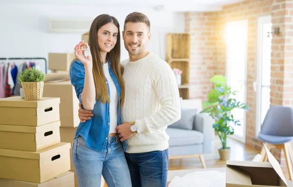年轻夫妇搬到一个新的家 拥抱在爱中显示新公寓的钥匙微笑着很高兴 — 图库照片