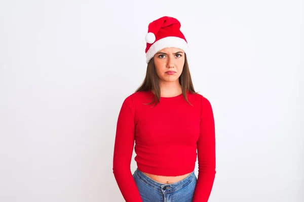 孤立した白い背景の上に立ってクリスマスサンタの帽子を身に着けている若い美しい女の子は落ち込んでおり 苦痛を心配し 怒って恐れて泣いています 悲しい表情 — ストック写真