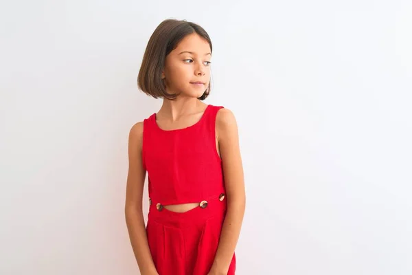 年轻美丽的小女孩穿着红色休闲装 站在孤零零的白色背景上 面带微笑地看着旁边 自然的表情 充满自信的笑 — 图库照片