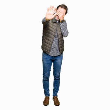 Orta giyen yakışıklı adam kış elleriyle gözlerini kapsayan yelek ve stop jest ile acı ve korku yaş ifade. Utandım ve negatif kavramı.