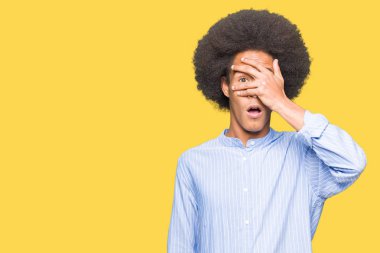 Yüz ve gözler el ile kapsayan şok bakmak afro saçlı genç Afro-Amerikan adam utanç ifadesi ile parmaklarımın arasından seyir.