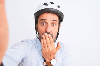 Bisiklet kaskı takan orta yaşlı bir işadamı, izole edilmiş beyaz arka plan üzerinde selfie çeker. Ağız, hata yüzünden utançla, korkunun dışavurumuyla, sessizlikten korkarak, gizli bir konseptle kaplanır.