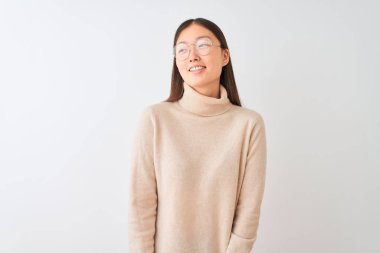 Balıkçı yaka kazak ve gözlük takan genç Çinli bir kadın izole edilmiş beyaz arka planda, yüzünde gülümseme, doğal bir ifade ile diğer tarafa bakıyor. Kendinden emin gülen.