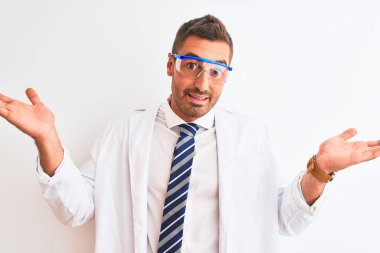 Güvenlik gözlüğü takan genç ve yakışıklı bir bilim adamı izole edilmiş arka planda bilgisiz ve elleri ve elleri havada kafası karışık bir ifade takınıyor. Şüphe kavramı.