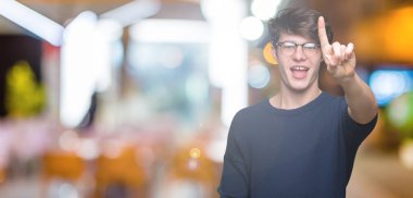 Ve kendinden emin ve mutlu gülümseyerek süre parmak numaralı yukarıyı gösteren izole arka plan üzerinde gözlük takan genç yakışıklı adam.