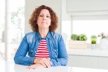 Orta yaşlı, kıvırcık saçlı, kot ceket giyen, uykulu ve yorgun görünen, yorgunluktan bitkin düşmüş, akşamdan kalma, tembel gözlü bir kadın..