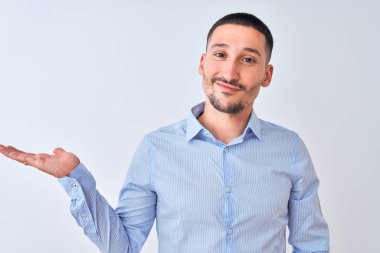 Genç yakışıklı iş adamı izole edilmiş arka planda durup mutlu bir şekilde sunum yapıyor ve avuç içi kameraya bakıyor..