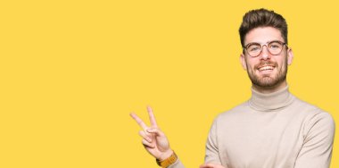 Mutlu yüz zafer işareti yaparken kameraya göz kırpıyor ile gülümseyen gözlüklü genç yakışıklı iş adamı. İki numaralı.