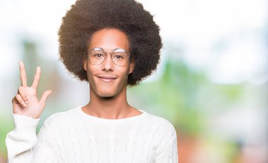Afro saçlı gösterilen ve parmakları ile işaret gözlüklü genç Afro-Amerikan adam kendinden emin ve mutlu gülümseyerek iken üçüncü.
