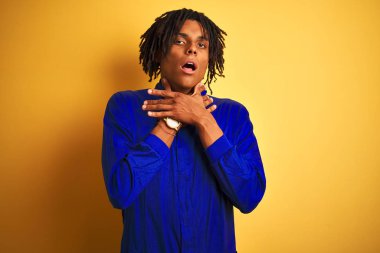 Sarı arka plan üzerinde mekanik üniforma giyen Afrikalı işçi bağırıyor ve boğuluyor çünkü acı verici bir boğulma. Sağlık problemi. Boğulma ve intihar konsepti.