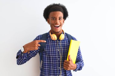 Afrika kökenli Amerikalı bir öğrenci, sırt çantalı, izole edilmiş beyaz bir arka plan ve kendini işaret eden sürpriz bir yüz.