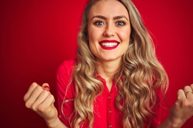 Kızıl arka planda duran genç ve güzel bir kadın gururla haykırıyor ve zaferi ve başarıyı kutluyor çok heyecanlı, coşkulu bir duygu.