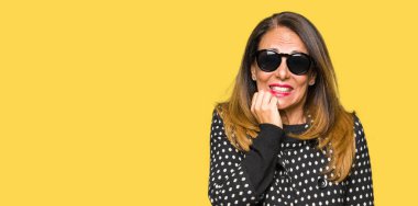 Güzel orta yaş kadın stresli ve gergin elle çivi ısırma ağzına bakarak güneş gözlüğü takıyor. Anksiyete sorunu.