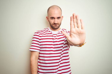Sakallı, beyaz izole edilmiş arka plan üzerine normal çizgili kırmızı tişört giyen genç kel bir adam avucunun içi gibi şarkı söylemeyi kesiyor. Yüzünde olumsuz ve ciddi bir jest olan uyarı ifadesi.