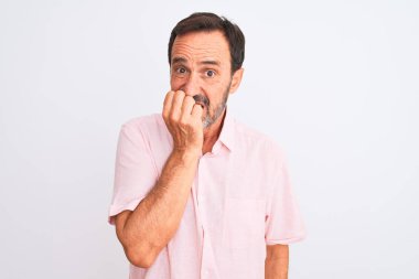 Orta yaşlı, pembe gömlekli yakışıklı bir adam izole edilmiş beyaz arka planda dikiliyor. Elleri ağız yiyen tırnak gibi gergin ve stresli görünüyor. Endişe sorunu.