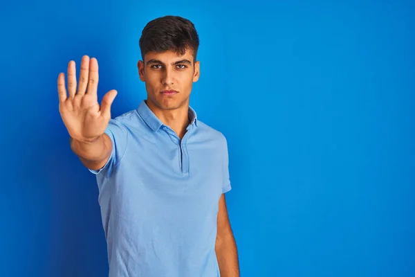 年轻的印度男子穿着休闲装 站在孤立的蓝色背景上 停止手心唱着歌 脸上带有消极而严肃的手势的警告表情 — 图库照片