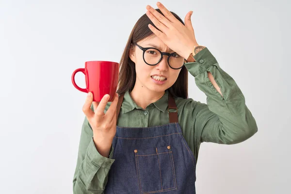 Chinese barista woman wearing apron glasses drinking coffee over isolated white background stressed with hand on head, shocked with shame and surprise face, angry and frustrated. Fear and upset for mistake.