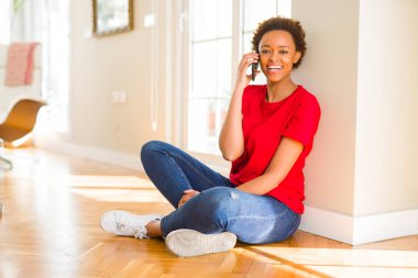 Telefon gülümseyen üzerinde muhabbet katta oturan güzel genç Afro-Amerikan kadın