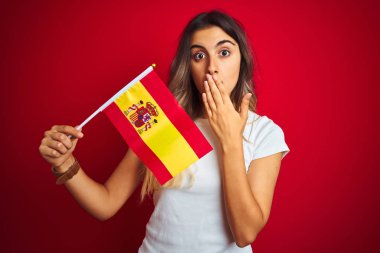 Young beautiful woman holding spanish flag over red isolated background cover mouth with hand shocked with shame for mistake, expression of fear, scared in silence, secret concept