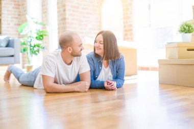 Yeni bir evin katında yatan aşık genç çift, yeni bir daireye taşınmak için çok mutlu gülümseyen, karton kutular civarı