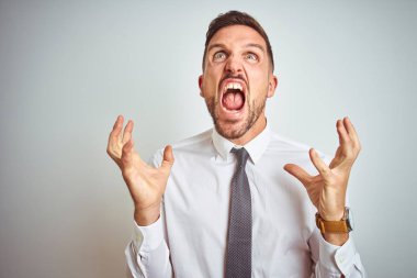 Soyutlanmış arka planda zarif beyaz gömlekler giyen genç yakışıklı iş adamı kızgın ve deli gibi bağırıyor ve agresif bir ifade ve kollarla bağırıyor. Hayal kırıklığı konsepti.