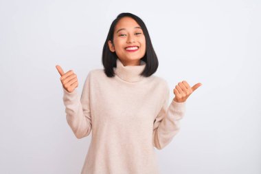 Balıkçı yaka kazak giyen genç bir kadın izole edilmiş beyaz arka plan başarısı tabelasının üzerinde duruyor. Elleriyle olumlu jest yapıyor, gülümsüyor ve mutlu. Neşeli ifade ve kazanan jest.