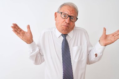 Kravat ve gözlük takan kıdemli gri saçlı işadamı izole edilmiş beyaz arka plan hakkında hiçbir şey bilmiyor ve elleri ve kolları havada kafası karışık bir ifade sergiliyor. Şüphe kavramı.
