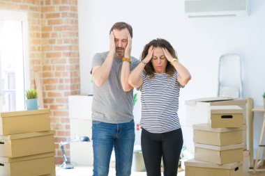 Orta yaş kıdemli çift baş ağrısı çaresiz muzdarip etrafında kutuları ile yeni bir eve hareket ve stres çünkü ağrı ve migren. Eller baş.