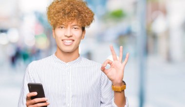 Yakışıklı delikanlı parmak, mükemmel sembolü ile ok işareti yapıyor smartphone kullanarak