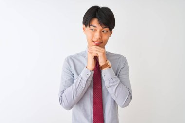 Çinli iş adamı zarif bir kravat takıyor. İzole edilmiş beyaz arka planda duruyor. Gergin ve heyecanlı bir şekilde çene kenarına bakıyor.