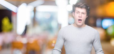 Şüpheci ve alaycı, şok karşısında izole arka plan üzerinde kış kazak giyen genç yakışıklı adam açık ağız ile şaşırttı