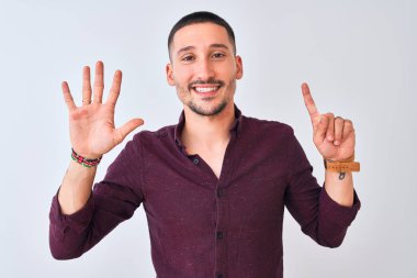 Young handsome business man standing over isolated background showing and pointing up with fingers number six while smiling confident and happy.