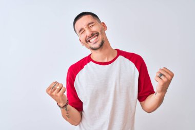 Young handsome man standing over isolated background very happy and excited doing winner gesture with arms raised, smiling and screaming for success. Celebration concept.