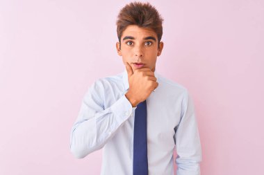 Genç yakışıklı işadamı gömlek ve kravat izole pembe arka plan üzerinde duran inançsızlık, sürpriz ve çene elleri ile hayran ifade hayran arıyorum