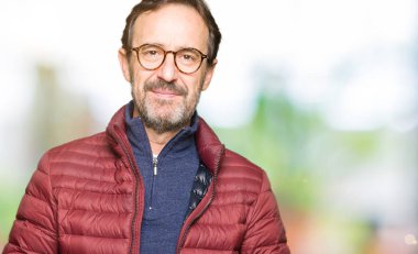 El ele tutusun ve rahat ve neşeli gülümseyen parmak çarpı işareti orta yaş yakışıklı adam gözlük ve kış ceket. Başarı ve iyimser