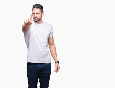 Beyaz yalıtılmış arka plan üzerinde beyaz tişört giyen yakışıklı bir adam. Parmağını kaldırmış ve kızgın bir ifade sergiliyor.