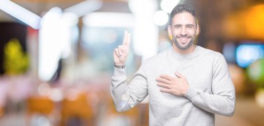 Genç yakışıklı adam giyen kazak izole üzerinde arka plan Swearing göğüs ve bir sadakat sözü yemin yapma parmaklar, el ile