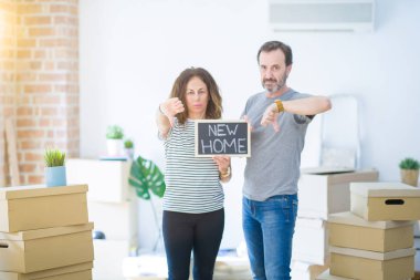 Orta yaşlı çift ellerinde karatahta ile kızgın yüzlü yeni bir eve taşınıyor. Negatif işaretler baş parmakları aşağıda, reddedilme konsepti ise reddedilmiş.
