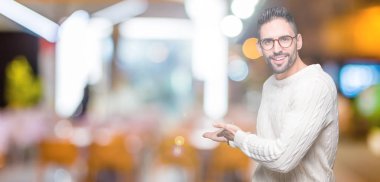 Açık el ile doğal gülümseyen girmek için davet izole arka plan üzerinde gözlük takan genç yakışıklı adam