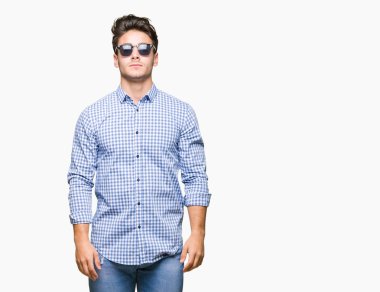 Genç yakışıklı adam yüzünde ciddi bir ifade ile izole arka plan üzerinde güneş gözlüğü takıyor. Basit ve doğal kameraya bakıyor.