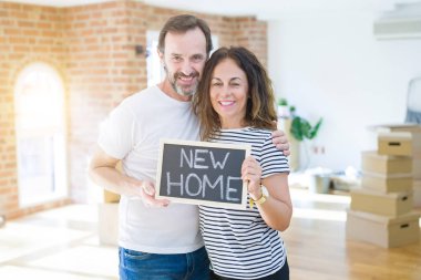 Orta yaş Senior çift yeni bir eve hareket, yeni bir ev metin ile bir tahta tutan Apartmant aşık mutlu gülümseyen