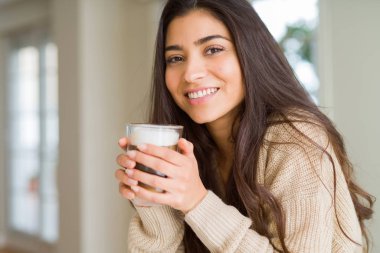 Güzel genç kız evde bir fincan kahve içme ve gülümseyen