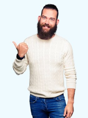 Seyir ve başparmak yanında yukarıyı mutlu yüz ile gülümseyen kış kazak giyen genç hipster adam.