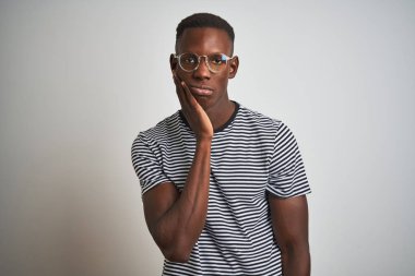Afrika kökenli Amerikalı bir adam çizgili tişört ve gözlük giyerek izole edilmiş beyaz arka plan üzerinde yorgun ve bunalımlı gözüktüğünü düşünüyordu..