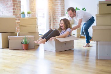 Orta yaş üst düzey romantik çift, eğlenceli karton içinde sürme, heyecanlı ve yeni bir eve taşımak için mutlu gülümseyen