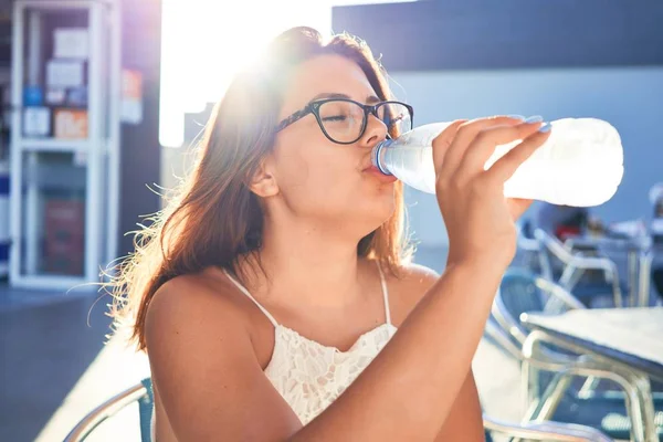 夏休みを楽しむレストランに座っている若い美しい女性水のボトルを飲む — ストック写真